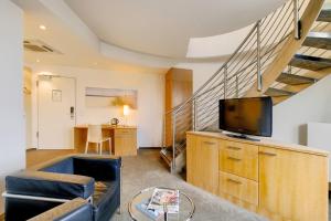 a living room with a television and a staircase at Hotel Berlin Mitte by Campanile in Berlin