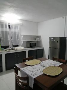una cucina con tavolo, sedie e frigorifero di Ô Bercail du Sud chez Jeannette a Rodrigues Island