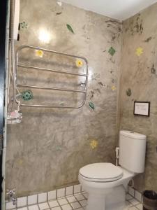 ein Bad mit einem WC und Blumen an der Wand in der Unterkunft Vlodge House in Chiang Mai