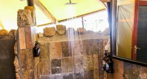 a shower in a room with a stone wall at Ondudu Safari Lodge in Omaruru