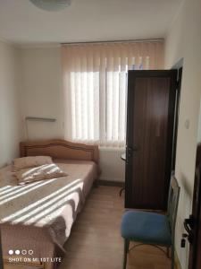 a bedroom with a bed and a chair and a window at Casa Rosa in Băile Olăneşti