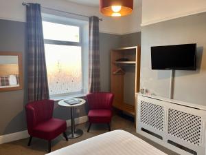 um quarto com uma cama e duas cadeiras e uma televisão em HK Rooms - Self Catering Rooms em Lowestoft