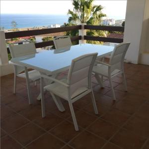 een witte tafel en stoelen op een balkon met uitzicht op de oceaan bij 2056 - Apt with terrace sea view in Manilva