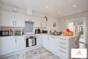a white kitchen with white cabinets and appliances at St Ives Bay - Immaculate Brand New 3Bed - Free Parking - Beach - WiFi in Hayle