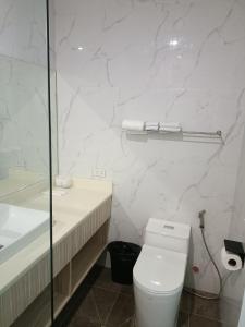 a white bathroom with a toilet and a sink at Rosh Hotel in Manila