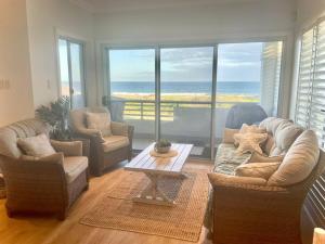 a living room with a couch and chairs and a table at Beach House on Stockton Beach, Newcastle in Stockton