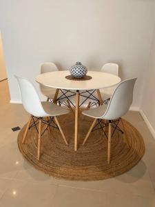 una mesa con cuatro sillas y un jarrón en ella en Beach House on Stockton Beach, Newcastle, en Stockton