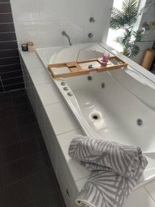 bañera blanca con bandeja de madera encima en Beach House on Stockton Beach, Newcastle en Stockton