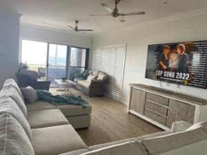 a living room with a couch and a flat screen tv at Beach House on Stockton Beach, Newcastle in Stockton
