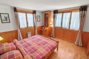 ein Schlafzimmer mit einem Bett und einigen Fenstern in der Unterkunft Logement spacieux et confortable in Chateau-d'Oex