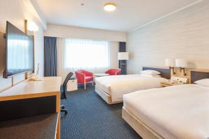 a hotel room with two beds and a desk at Hotel Nikko Narita in Narita
