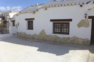 a white house with a stone wall and a building at Cuevas Don Alvaro y Romaide 
