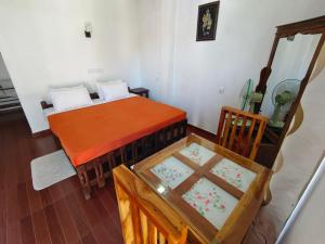 a bedroom with a bed and a table and a chair at Richard Homestay in Ella