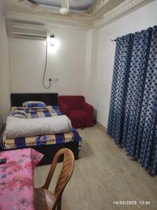 a bedroom with a bed and a red chair at Short stay service apartment in Dhaka