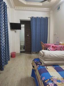 a room with blue curtains and a bed and a television at Short stay service apartment in Dhaka