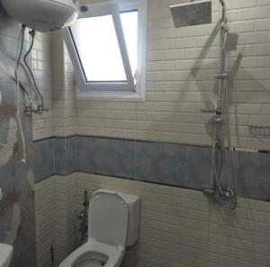 uma casa de banho com um WC, uma janela e um chuveiro em شاطئ المعموره em Alexandria