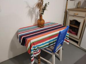 une table avec un tissu de table rayé coloré et une chaise bleue dans l'établissement Sur les bords de Loire, à Montlouis-sur-Loire