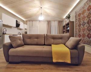 ein braunes Sofa im Wohnzimmer mit gelbem Stuhl in der Unterkunft NORDIC уютный домик в скандинавском стиле в горах Алматы in Besqaynar