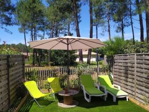 une terrasse avec des chaises, une table et un parasol dans l'établissement Guest house privative pour 2 sur Lege cap Ferret, à Lège