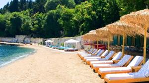 uma praia com cadeiras e guarda-sóis e a água em RetroNuovo em Corfu Town