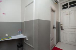 La salle de bains est pourvue d'une porte blanche et d'un tapis rouge. dans l'établissement RedDoorz Plus @ Kemayoran, à Jakarta