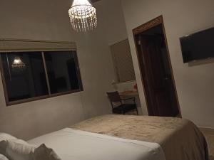 a bedroom with a bed and a chandelier and a window at HOTEL LA POSADA DEL ZAGUÁN in El Retiro