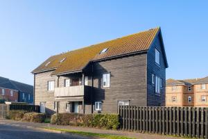 uma casa grande com um telhado preto numa rua em The Quarter Deck em Aldeburgh