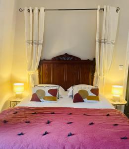 ein Schlafzimmer mit einem großen Bett mit einer rosa Decke in der Unterkunft La bohème - Chambres d’hôtes in Senlis