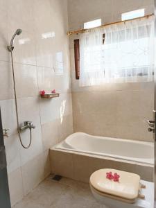 a bathroom with a tub and a toilet and a sink at Meninting garden house in Montongbuwoh +20 photos