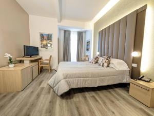 1 dormitorio con 1 cama y escritorio con TV en Hotel Mioni Royal San, en Montegrotto Terme