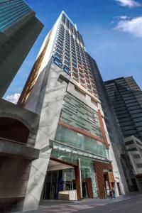 香港にあるNina Hotel Kowloon Eastの都市にあるガラス窓のある高層ビル