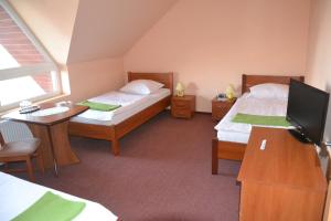 a room with two beds and a desk and a tv at Hotelik Orlik in Legnickie Pole
