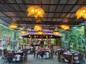 a restaurant with tables and chairs and chandeliers at Phu Ninh Lake Resort & Spa in Tam Kỳ