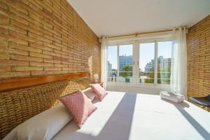 um quarto com uma parede de tijolos e uma cama com almofadas em HomeHolidaysRentals Miracel - Costa Barcelona em Malgrat de Mar