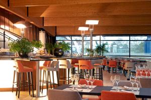 a restaurant with a bar with orange chairs and tables at d'Coque Hotel in Luxembourg