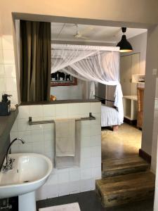 a bathroom with a sink and a mirror and a bed at Africa House Malawi in Lilongwe