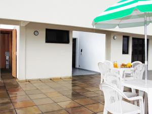 ein Esszimmer mit weißen Stühlen und einem Sonnenschirm in der Unterkunft Scala Residence Hotel in Resende