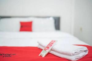 a pile of towels sitting on top of a bed at RedDoorz Syariah Near Syamsudin Noor Airport 4 in Ulin