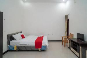 1 dormitorio con cama, escritorio y ordenador en RedDoorz Syariah Near Syamsudin Noor Airport 4, en Ulin
