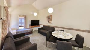 ein Wohnzimmer mit einem Sofa, einem Tisch und Stühlen in der Unterkunft Executive Hideaway in Benalla