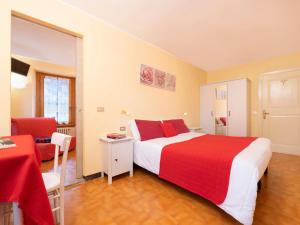 - une chambre avec un lit rouge et blanc et une chaise dans l'établissement Mondo D'Oro, à Macugnaga
