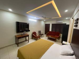 um quarto de hotel com uma cama e uma televisão e cadeiras em UPPERCREST RESIDENCY PALA em Pala
