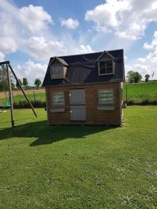 une petite maison dans une cour avec une balançoire dans l'établissement Gîte au cœur de la campagne, à Saint-Gilles