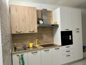 una cocina con armarios blancos y fregadero en Einaudi Apartment en Cologno Monzese