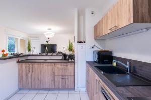 een keuken met houten kasten en een wastafel bij Location appartement 3 étoiles - 5 personnes in Le Pradet