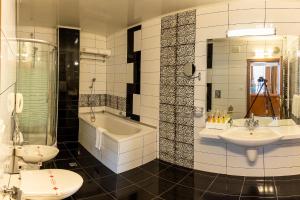 a bathroom with two sinks and a tub and a toilet at Hotel Palas in Kazanlŭk
