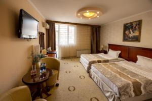 a hotel room with two beds and a flat screen tv at Hotel Palas in Kazanlŭk