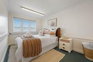 a white bedroom with a bed and a window at The Bungalow in Hamilton