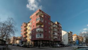 Un alto edificio rosso su una strada cittadina di Central Fenix apartment - Free private parking-Fast WI-FI a Novi Sad