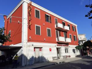 un edificio rojo y blanco con un hombre parado frente a él en Hotel Ristorante Moderno, en SantʼAntìoco